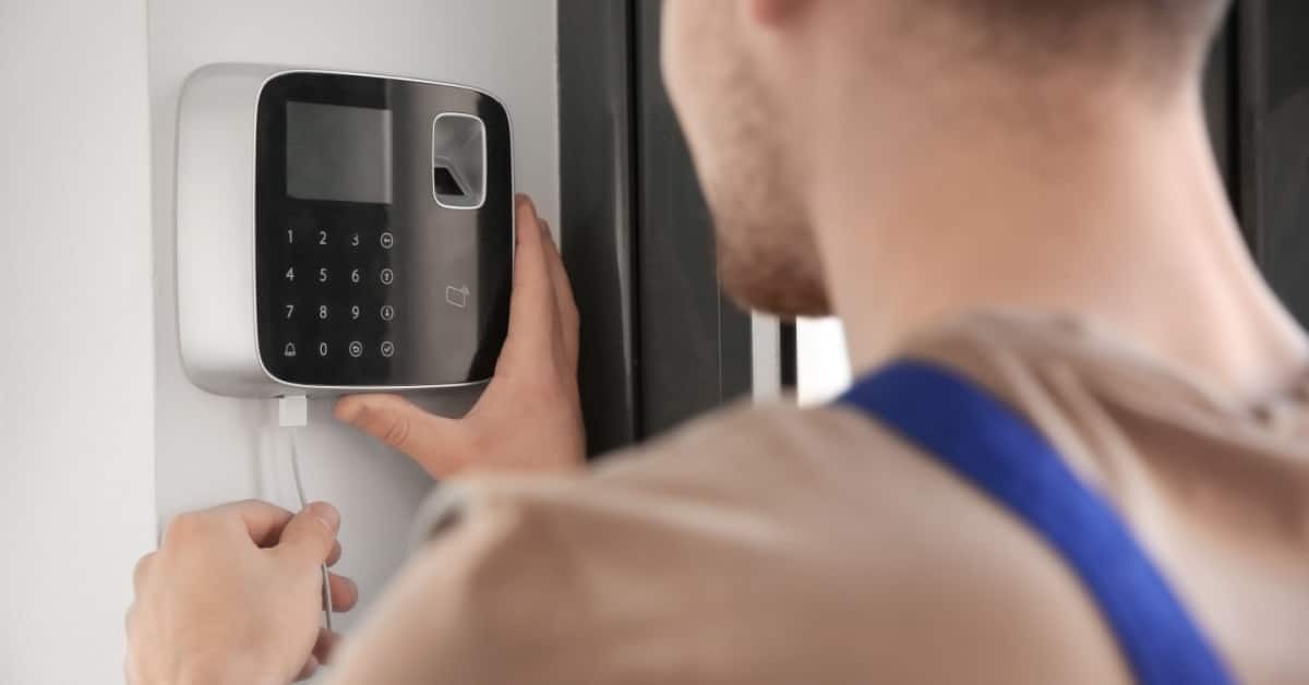 Un homme en combinaison installe une alarme de sécurité dans la maison
