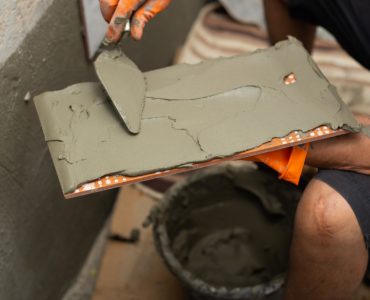 Un homme en train de poser le carrelage sur un mur en béton