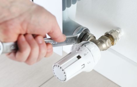 Zoom sur la main d'un homme réparant un radiateur électrique avec une clé