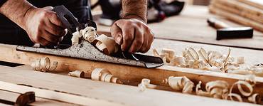 Un homme en train de raboter une planche en bois