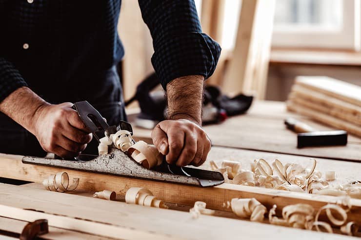 Un homme en train de raboter une planche en bois