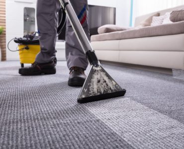 Un homme nettoyant la moquette du salon à l'aide d'un appareil