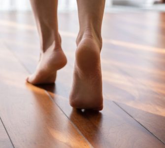 Une femme marche pieds nus sur la pointe des pieds dans une pièce en parquet