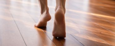 Une femme marche pieds nus sur la pointe des pieds dans une pièce en parquet