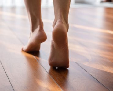 Une femme marche pieds nus sur la pointe des pieds dans une pièce en parquet