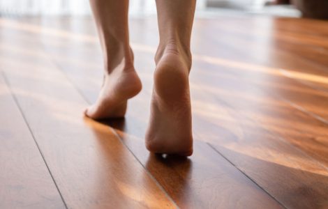 Une femme marche pieds nus sur la pointe des pieds dans une pièce en parquet