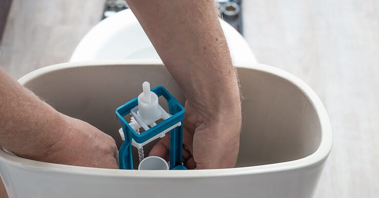 Zoom sur les mains d’un homme réparant la chasse d’eau