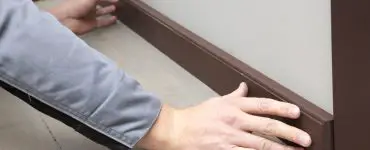 Mains d'un homme installant une plinthe
