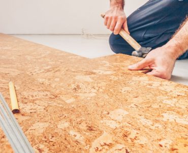 Un homme accroupi installant des dalles de sol en liège