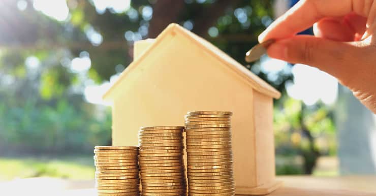 Une maquette maison et des pièces de monnaies pour illustrer le concept économiser pour une maison