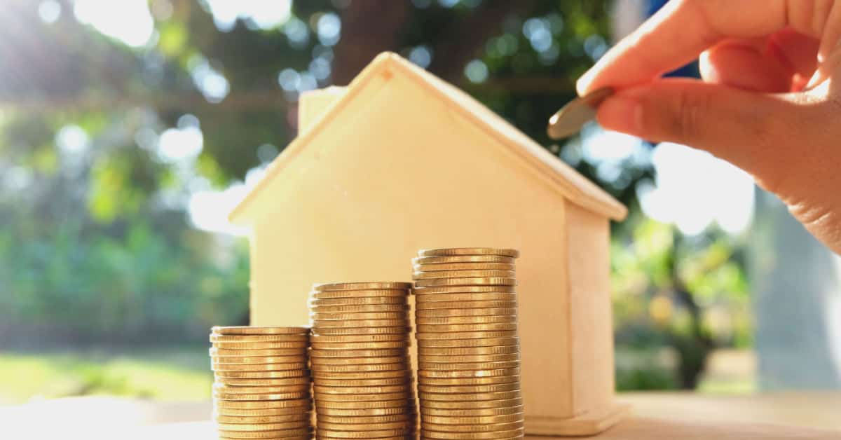 Une maquette maison et des pièces de monnaies pour illustrer le concept économiser pour une maison