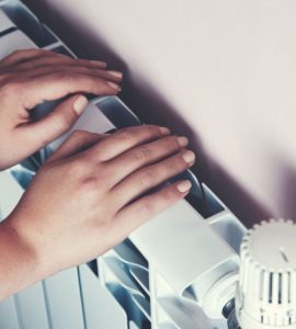 Zoom sur les mains d'un enfant posées sur le radiateur de la maison