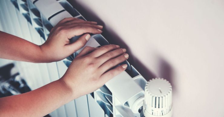 Zoom sur les mains d'un enfant posées sur le radiateur de la maison