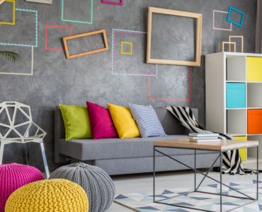 Grand salon moderne avec un canapé gris et des oreillers et poufs colorés