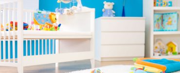 Une chambre bébé tout en couleur avec des jouets sur un tapis blanc