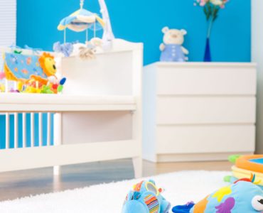 Une chambre bébé tout en couleur avec des jouets sur un tapis blanc