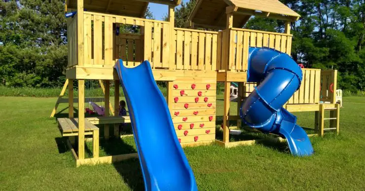 Une structure de jeu en bois et un balancier installés dans le jardin