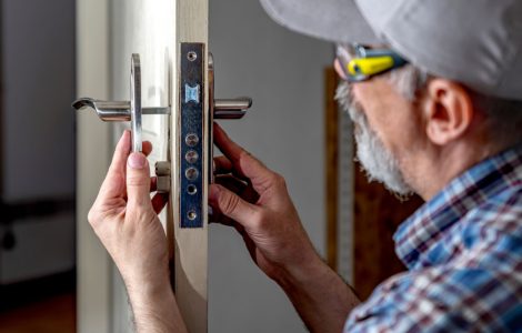 Un vieil homme en casquette répare les serrures d'une porte