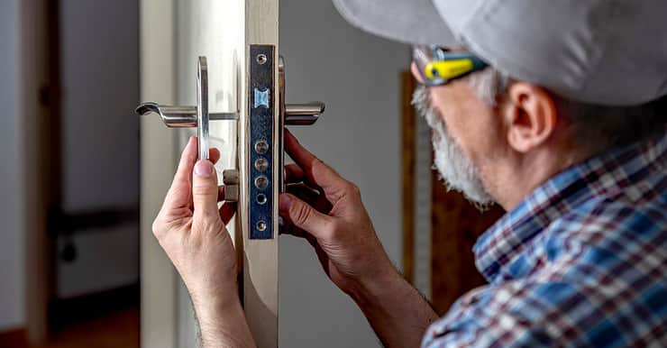 Un vieil homme en casquette répare les serrures d'une porte
