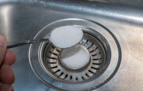 Une main versant du sel dans l'évier de cuisine avec une petite cuillère