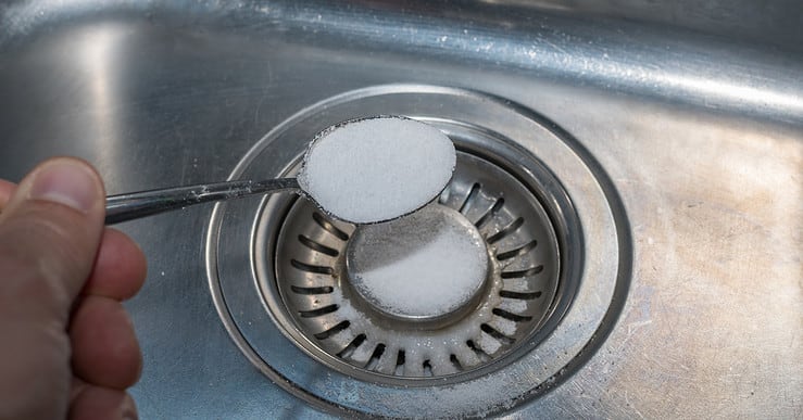 Une main versant du sel dans l'évier de cuisine avec une petite cuillère