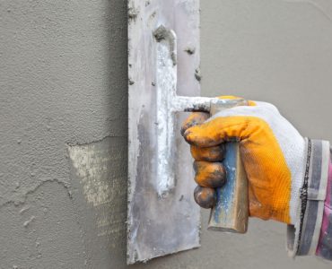 Zoom sur la main d’un homme étalant du mortier sur le mur à l’aide d’une truelle