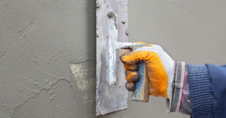 Zoom sur la main d’un homme étalant du mortier sur le mur à l’aide d’une truelle