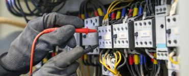 Zoom sur les mains d’un électricien qui vérifie la tension du courant électrique sur le tableau électrique