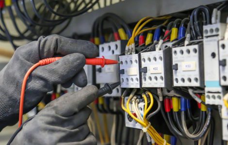 Zoom sur les mains d’un électricien qui vérifie la tension du courant électrique sur le tableau électrique