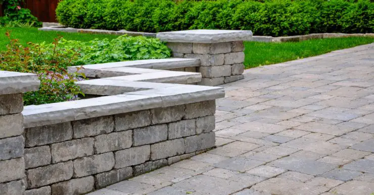 Un mur de sièges avec des piliers et des gravures en pierre naturelle permet de définir une allée pavée