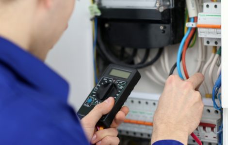 Un homme mesurant la tension dans le tableau électrique