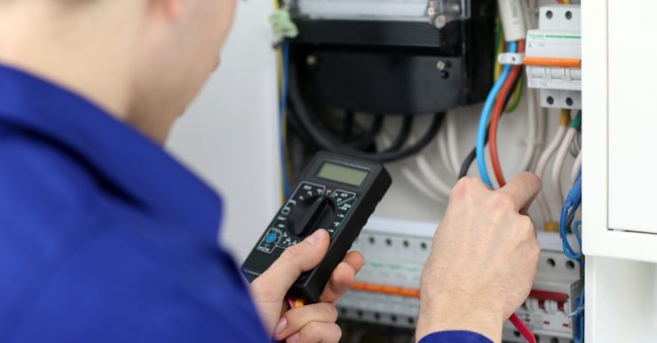 Un homme mesurant la tension dans le tableau électrique