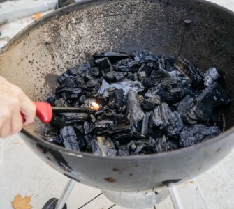 Une personne allumant le feu dans un gril à charbon à l'aide d'un briquet