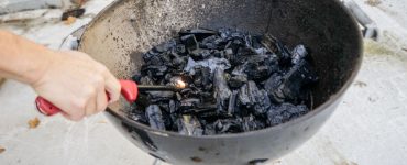 Une personne allumant le feu dans un gril à charbon à l'aide d'un briquet