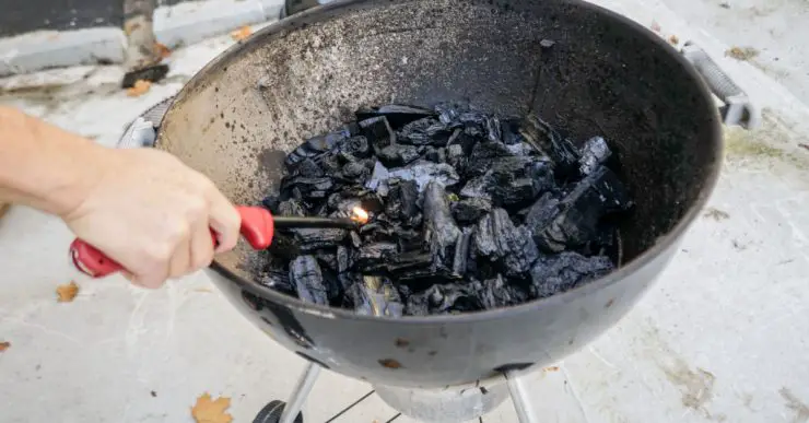 Une personne allumant le feu dans un gril à charbon à l'aide d'un briquet