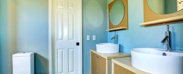 Une salle de bain bleue avec deux vasques distinctes et deux miroirs