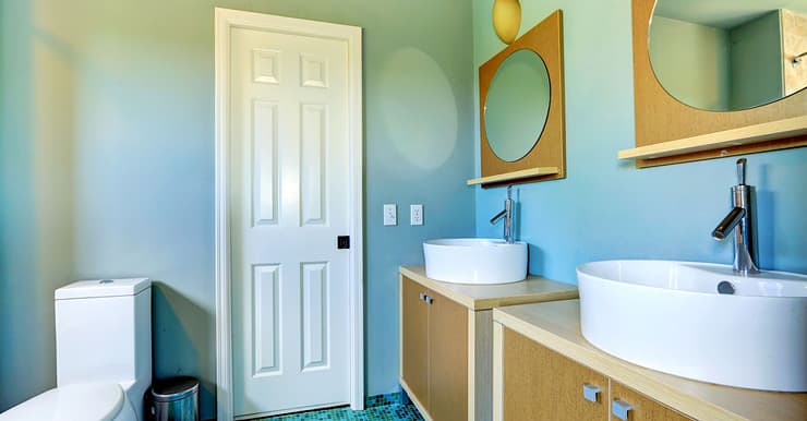 Une salle de bain bleue avec deux vasques distinctes et deux miroirs