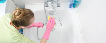 Une femme en gants roses nettoie la baignoire