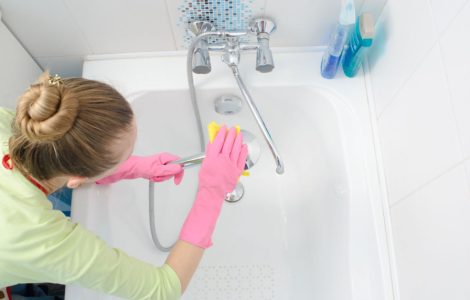 Une femme en gants roses nettoie la baignoire