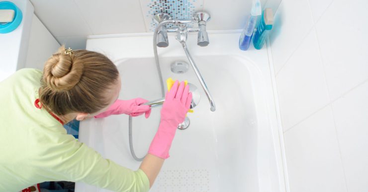 Une femme en gants roses nettoie la baignoire