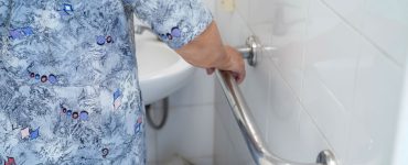 Une femme âgée dans la salle de bain tient une barre d'appui