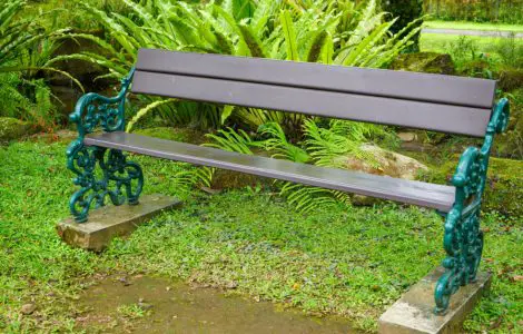 Une longue chaise en bois, avec cadre en fer dans un jardin