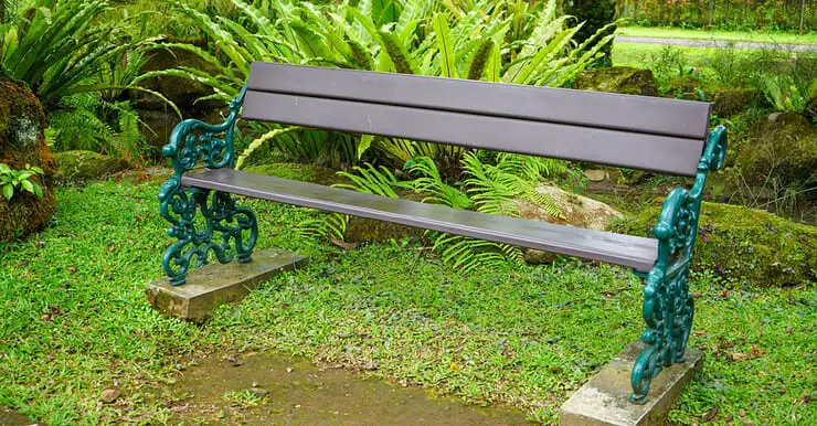 Une longue chaise en bois, avec cadre en fer dans un jardin