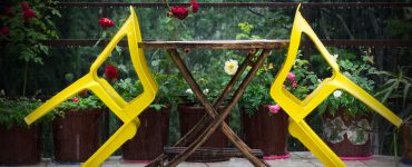 Deux chaises jaunes en plastique s’appuyant sur une table en bois à l’extérieur