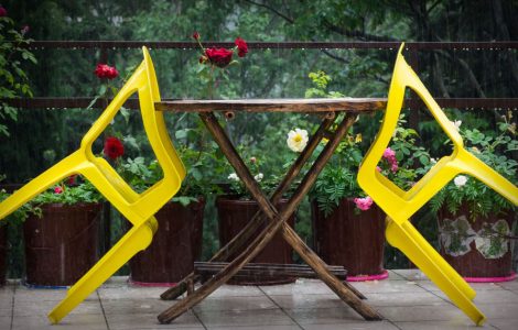 Deux chaises jaunes en plastique s’appuyant sur une table en bois à l’extérieur