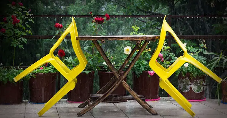 Deux chaises jaunes en plastique s’appuyant sur une table en bois à l’extérieur
