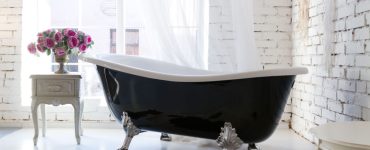 Une baignoire classique noire et blanche à côté de la fenêtre