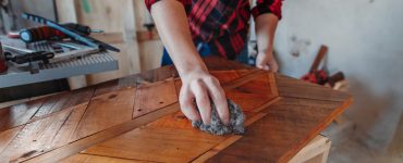 Un homme en train de cirer un meuble en bois dans son atelier