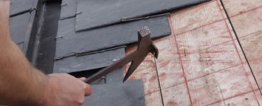 Zoom sur les mains d’un homme installant une toiture en ardoise