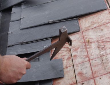 Zoom sur les mains d’un homme installant une toiture en ardoise